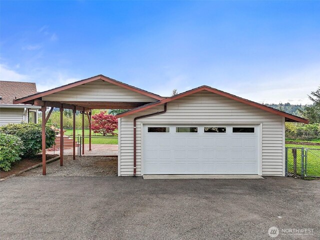 garage with aphalt driveway, fence, and a garage
