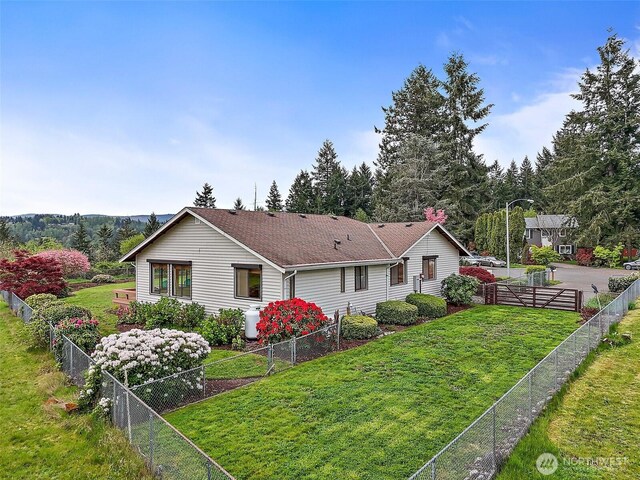 view of front of house with a fenced backyard, roof with shingles, and a front lawn