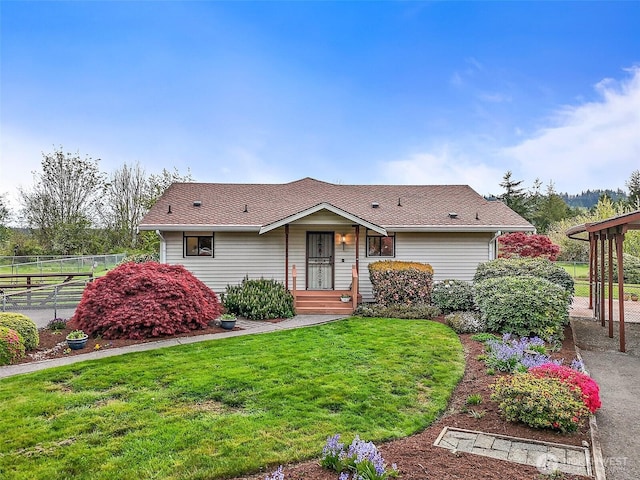 single story home with fence, a shingled roof, and a front yard