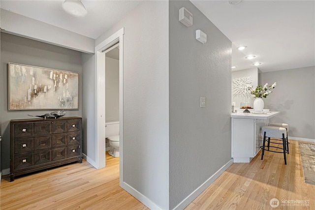 corridor with baseboards and wood finished floors