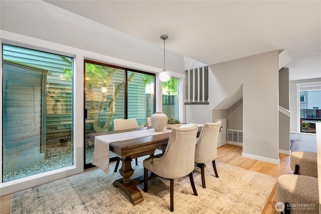 dining room with a healthy amount of sunlight, baseboards, light wood-type flooring, and visible vents