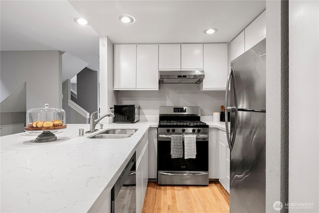 kitchen featuring white cabinetry, under cabinet range hood, light stone counters, a sink, and stainless steel appliances
