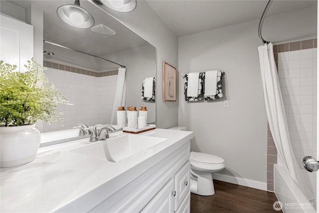 bathroom with wood finished floors, shower / tub combo, baseboards, vanity, and toilet