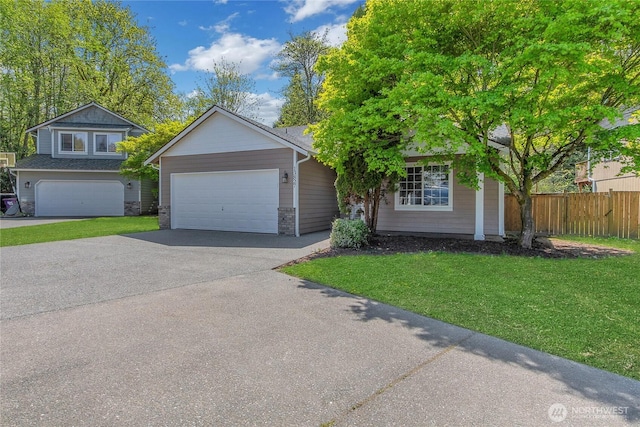 view of front of home with a front lawn, a garage, driveway, stone siding, and fence