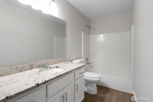 bathroom featuring wood finished floors, toilet,  shower combination, and vanity