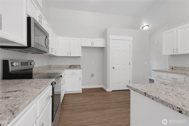 kitchen with light stone countertops, wood finished floors, appliances with stainless steel finishes, white cabinets, and baseboards