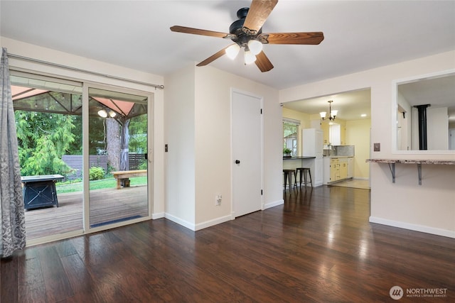 unfurnished living room featuring baseboards, ceiling fan with notable chandelier, and wood finished floors