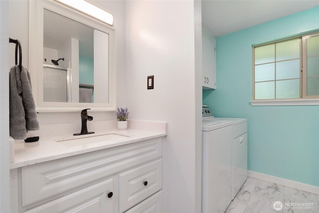 bathroom featuring two vanities, a sink, baseboards, marble finish floor, and separate washer and dryer