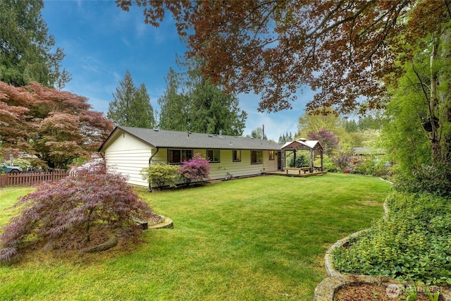 rear view of house with a lawn, a gazebo, and fence