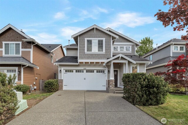 craftsman inspired home with concrete driveway, an attached garage, and stone siding