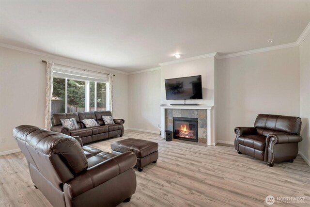 living area featuring baseboards, ornamental molding, light wood finished floors, and a tile fireplace