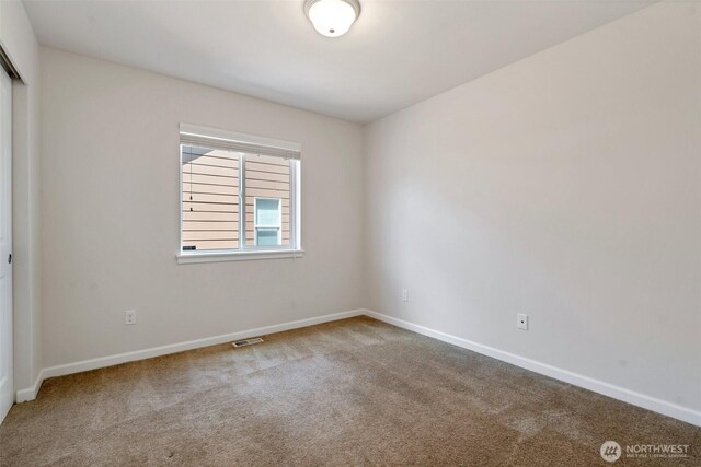 carpeted spare room featuring baseboards and visible vents