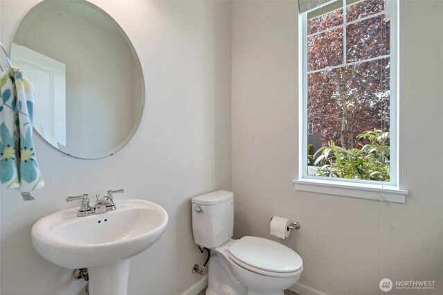 bathroom with toilet, baseboards, and a sink