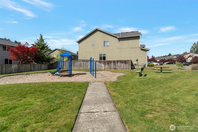 view of playground with fence and a lawn