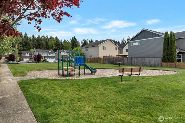 communal playground with fence, a yard, and a residential view