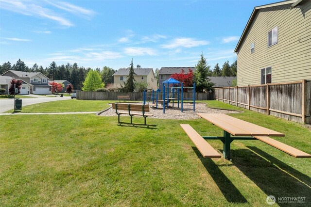 view of property's community with fence, a playground, a yard, and a residential view