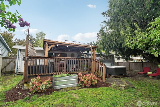 back of property featuring a hot tub, fence, a deck, and metal roof