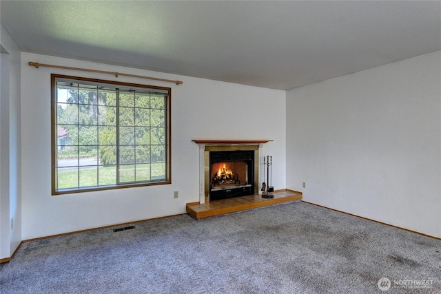unfurnished living room with carpet floors, visible vents, and a healthy amount of sunlight