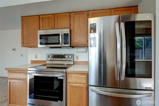 kitchen featuring light countertops, stainless steel appliances, and brown cabinets