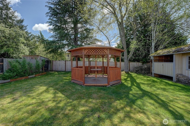 view of yard featuring an outdoor structure, a deck, a gazebo, and a fenced backyard