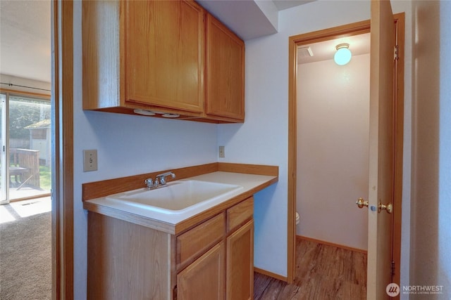 kitchen with a sink, light countertops, and light wood-style floors