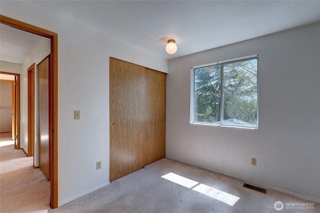 unfurnished bedroom with visible vents, carpet, and a closet