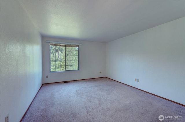 carpeted spare room with baseboards and visible vents