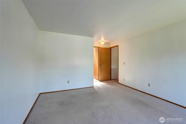 unfurnished room with baseboards and light carpet