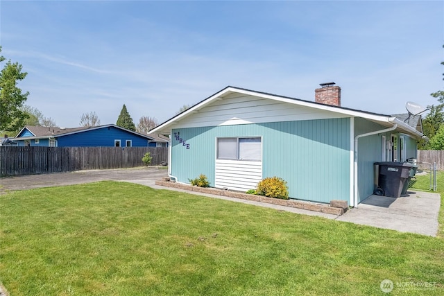 back of property with a lawn, fence, and a chimney