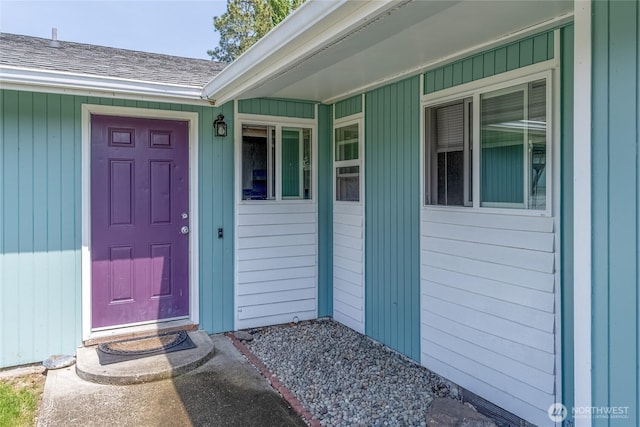 entrance to property featuring roof with shingles