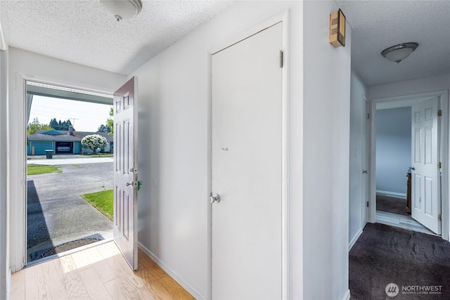 foyer featuring a textured ceiling and baseboards