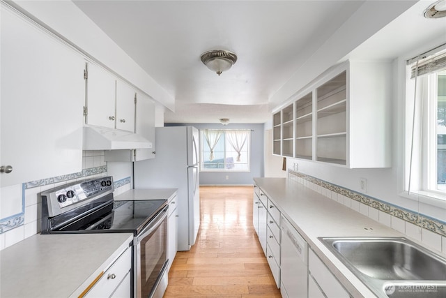 kitchen with white dishwasher, electric range, a sink, light wood-style floors, and under cabinet range hood