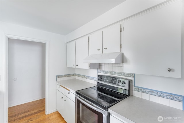 kitchen featuring white cabinets, electric range, light countertops, light wood-style flooring, and under cabinet range hood