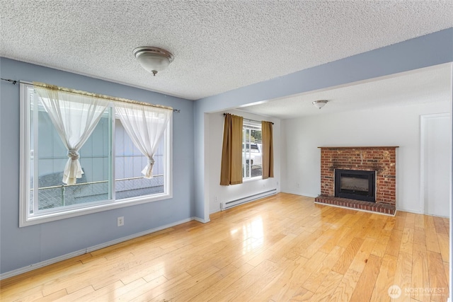 unfurnished living room with a textured ceiling, a fireplace, wood finished floors, baseboards, and a baseboard heating unit