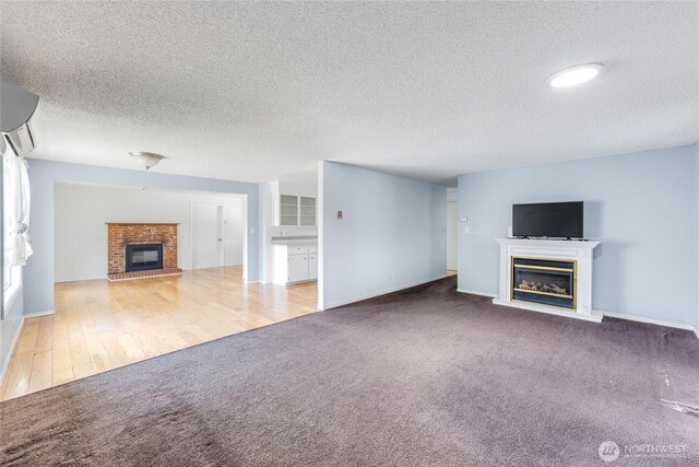 unfurnished living room with carpet floors, baseboards, a fireplace, and a textured ceiling