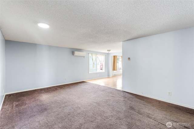 spare room with baseboards, a textured ceiling, carpet, and a wall unit AC