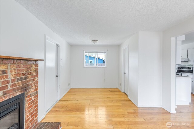 hall with light wood-type flooring and a textured ceiling