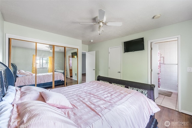 bedroom with connected bathroom, a ceiling fan, wood finished floors, and a closet