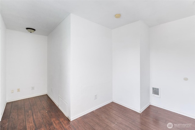 empty room featuring baseboards, visible vents, and wood finished floors