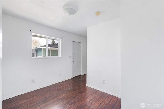 spare room featuring baseboards and wood finished floors