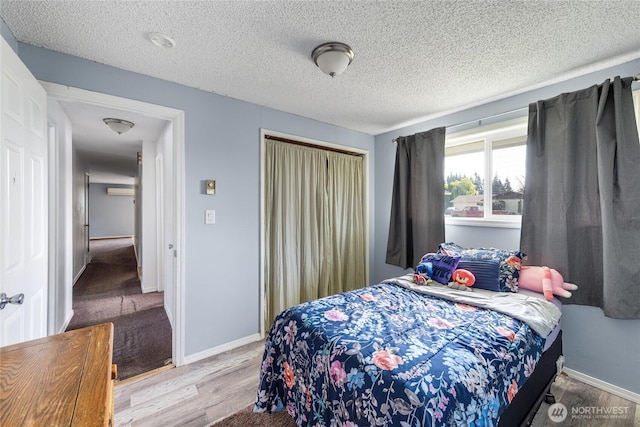 bedroom featuring a closet, baseboards, a textured ceiling, and wood finished floors