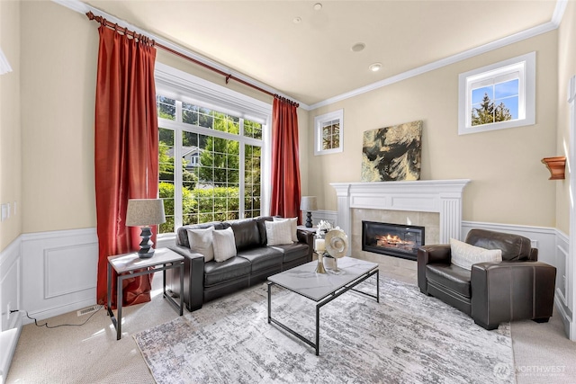 carpeted living area with crown molding, a decorative wall, wainscoting, and a tile fireplace