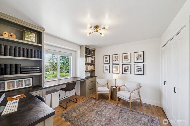sitting room featuring an inviting chandelier, built in study area, and light wood-style floors