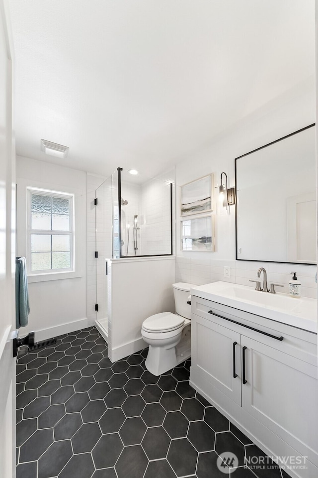 bathroom featuring toilet, a shower stall, tile patterned flooring, and vanity