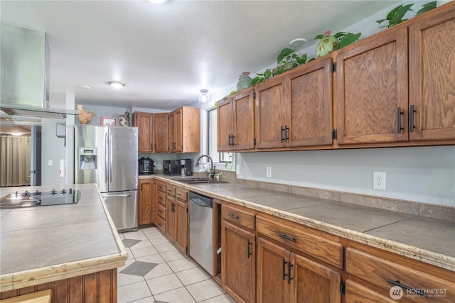 kitchen featuring brown cabinetry, stainless steel appliances, light tile patterned floors, light countertops, and a sink
