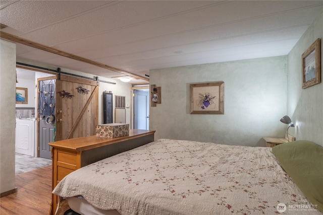 bedroom featuring light wood-style flooring, a barn door, and washer / clothes dryer