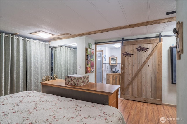 bedroom featuring a barn door, baseboards, and light wood-style floors