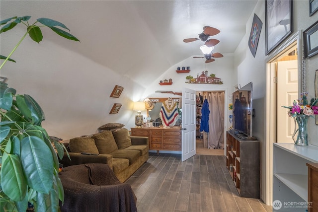 living area with ceiling fan, vaulted ceiling, and dark wood finished floors