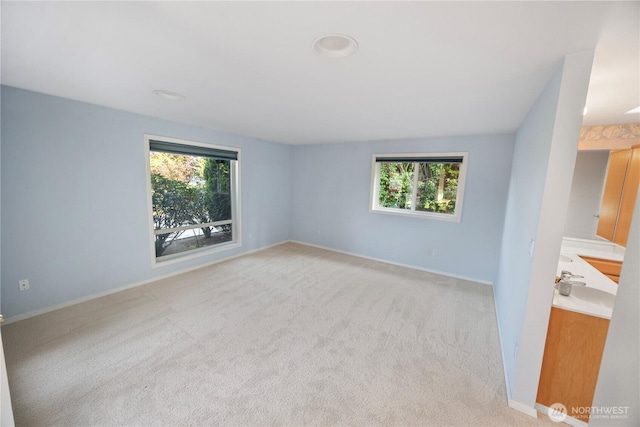 spare room with baseboards and light colored carpet