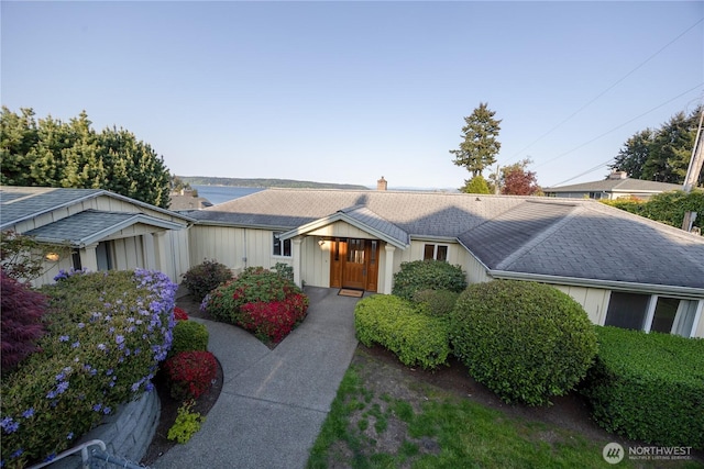 ranch-style home featuring a chimney and a shingled roof